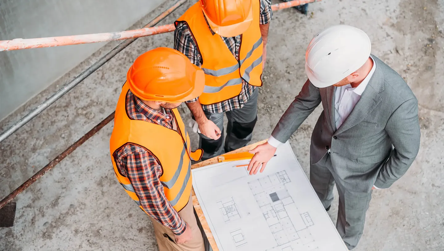 Construction workers review retail building permits on site with blueprint